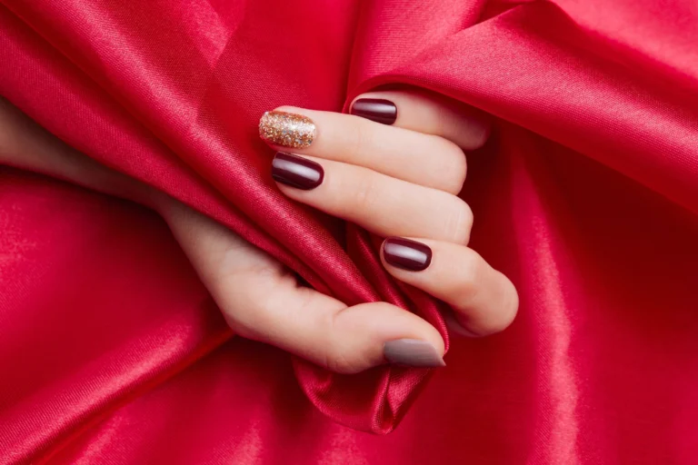 closeup-shot-female-s-hand-with-beautiful-nail-polish-caressing-red-silk-fabric