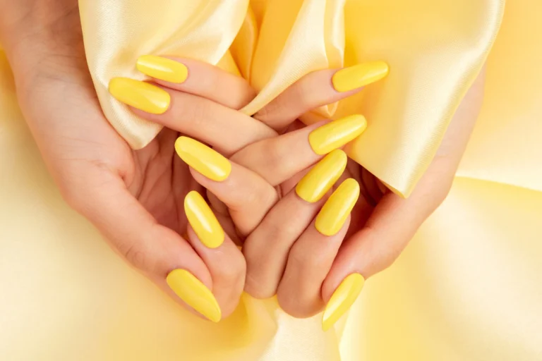 closeup-shot-female-s-hands-with-yellow-nail-polish-yellow-silk-fabric