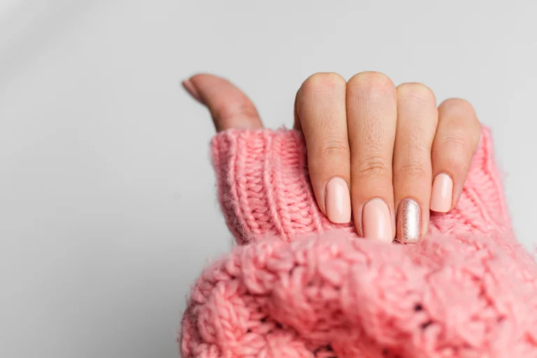 pretty-nude-color-manicure-one-finger-shiny-golden-knitted-pink-wool-pillover-background